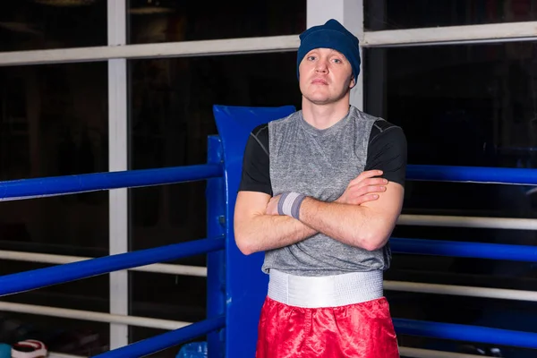 Boxeador atlético con brazos cruzados de pie en un rin de boxeo regular —  Fotos de Stock