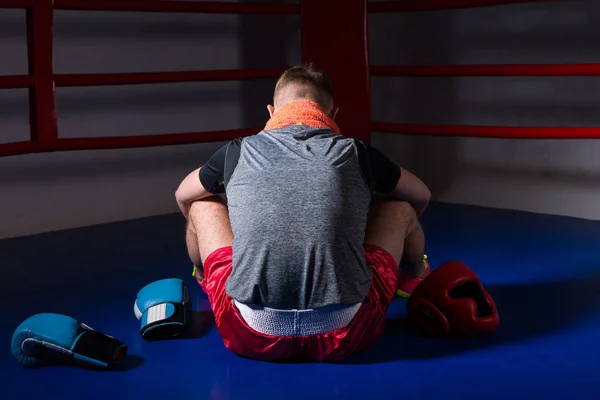 Joven boxeador masculino con una toalla alrededor de su cuello sentado hacia atrás — Foto de Stock