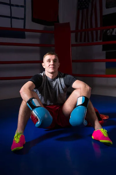 Joven boxeador deportivo en guantes de boxeo sentado en boxi regular —  Fotos de Stock