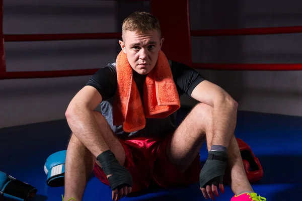 Junge männliche Boxer mit einem Handtuch um den Hals sitzt in regelmäßigen — Stockfoto