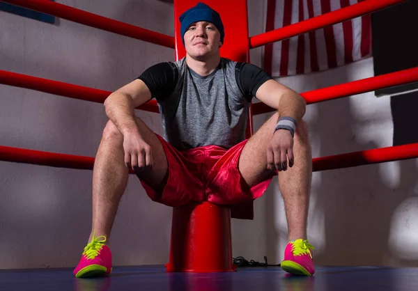 Spotive joven boxeador masculino sentado cerca de la esquina roja de un bo regular — Foto de Stock