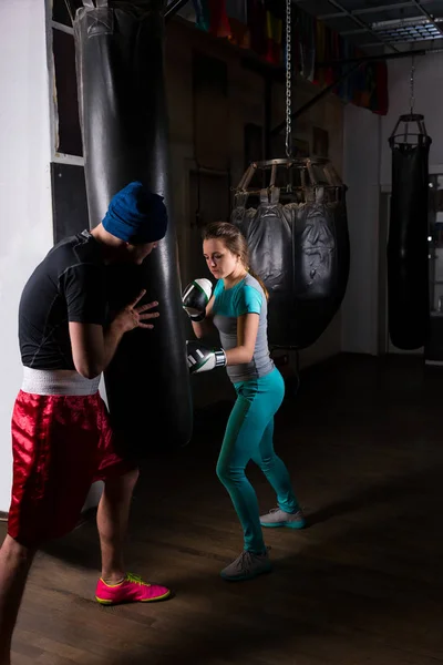 Mujer boxeador spoty en el entrenamiento de guantes de boxeo con su entrenador un —  Fotos de Stock
