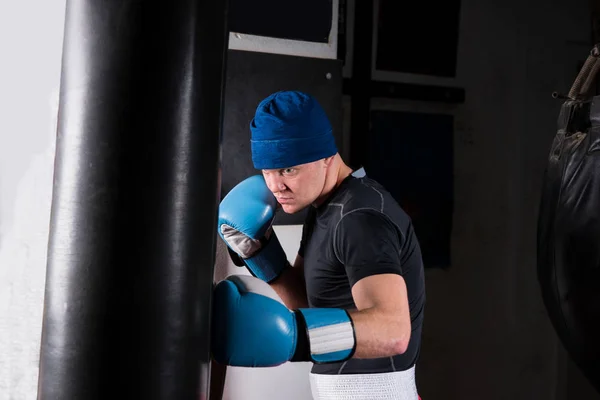 Young sporty male boxer in boxing gloves training with boxing pu — Stock Photo, Image