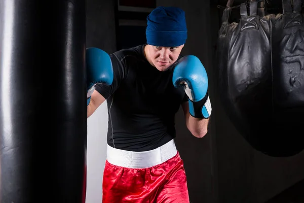 Boxeador deportivo en entrenamiento de guantes de boxeo con saco de boxeo — Foto de Stock