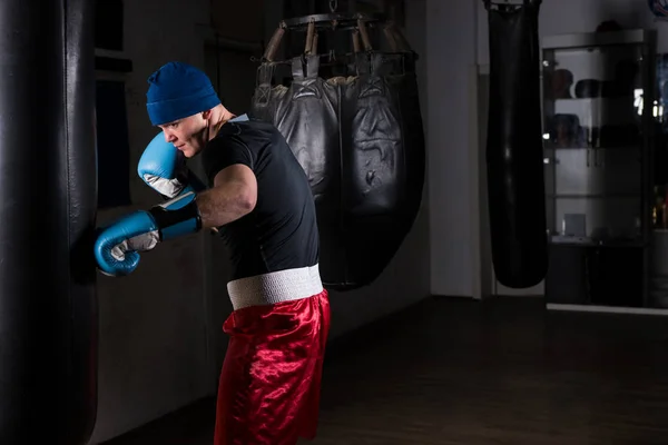 Молодой мужчина в шляпе и боксерских перчатках тренируется с боксерским пуншем — стоковое фото