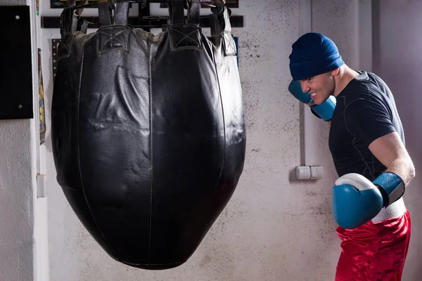 Boxer arrabbiato con sguardo severo in un cappello e guanti da boxe formazione — Foto Stock