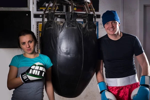 Ung sportig par i boxning handskar står nära boxning punchi — Stockfoto