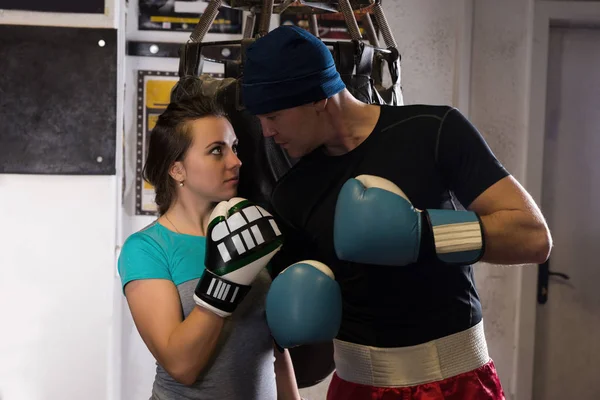 Sportig par i boxning handskar står nära boxning slagsäck — Stockfoto