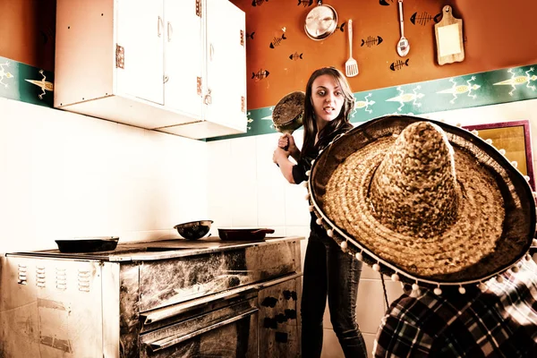 Junge wütende Frau schwenkt eine Pfanne auf einen Mann im Sombrero — Stockfoto