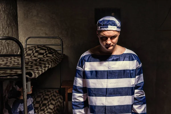Злой заключенный в тюремной форме, стоящий рядом с кроватью — стоковое фото