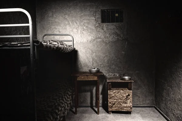 Тёмная пустая тюремная камера с двухъярусной кроватью и тумбочкой — стоковое фото