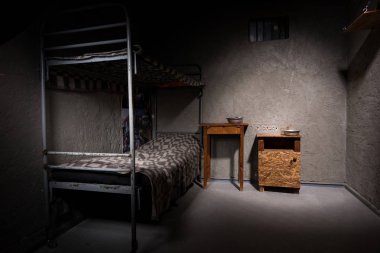 Jail cell with iron bunk bed and wooden bedside table clipart