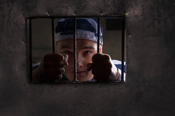 Vista através de porta de ferro com barras de prisão em prisioneiro masculino segurando — Fotografia de Stock