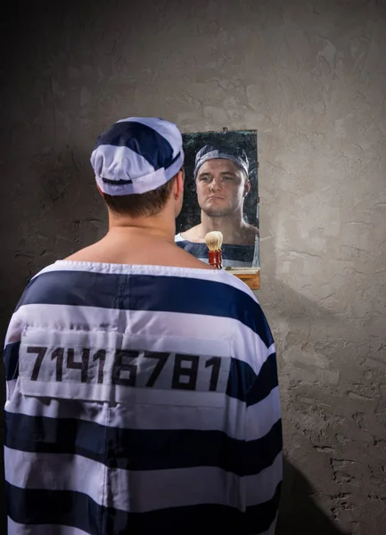 Angry prisoner standing and looking at his reflection in the mir — Stock Photo, Image