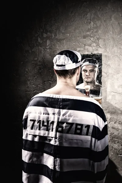 Angry male prisoner standing and looking at his reflection in th — Stock Photo, Image