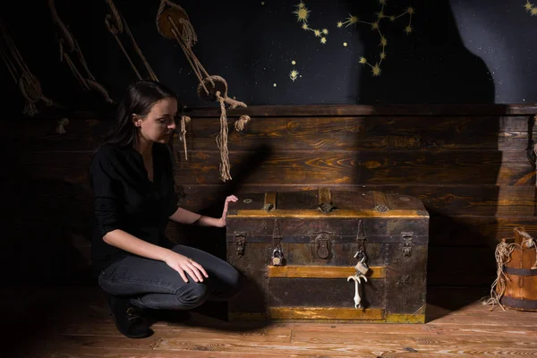 A young girl sits near a chest and trying to find a solution of — Stock Photo, Image