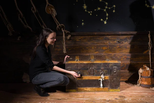 Young girl sits near a chest and trying to find a solution of co — Stock Photo, Image