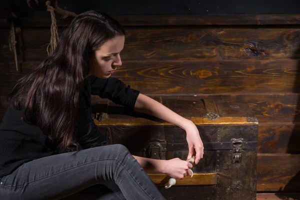 Молодая девушка сидит рядом с сундуком и пытается решить головоломку — стоковое фото