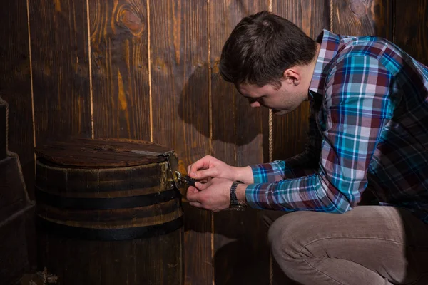 Joven se sienta cerca de un barril y tratando de resolver un enigma a — Foto de Stock