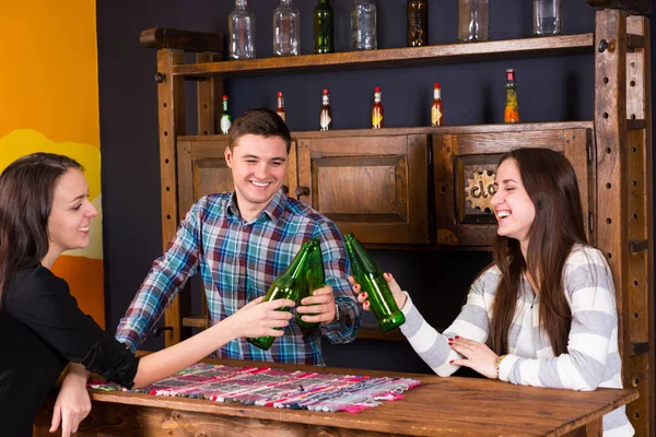 A company of young people clinking bottles of beer while standin — Stock Photo, Image