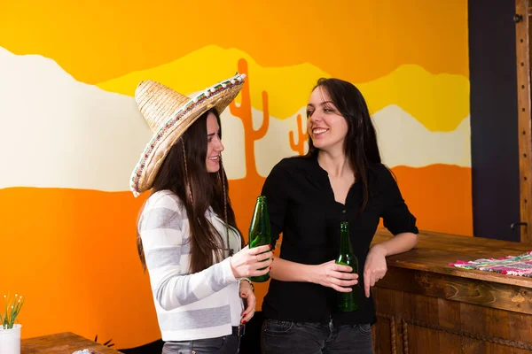 Mulheres jovens sorrindo bebendo cerveja no balcão do bar — Fotografia de Stock