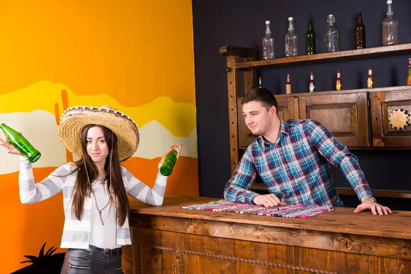 A young woman in a sombrero holding two bottles of beer and stan — Stock Photo, Image