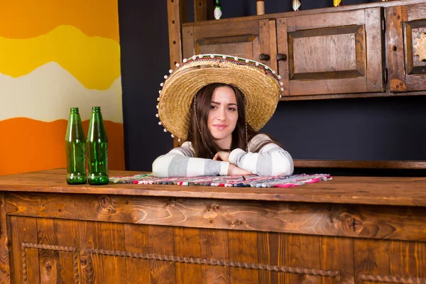 A young woman in a sombrero leaned on bar counter in Mexican pub — Stock Photo, Image