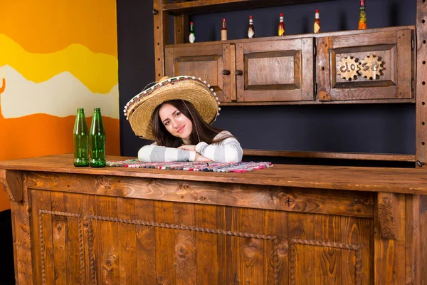 Bella giovane donna in un sombrero appoggiata sul bancone del bar a Mex — Foto Stock