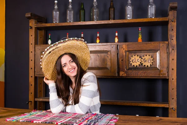 Mooie lachende jonge vrouw in een sombrero leunde op bar counte — Stockfoto