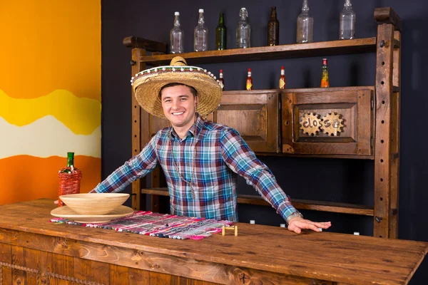 Smiling handsome male bartender in a sombrero standing at the co — Stock Photo, Image