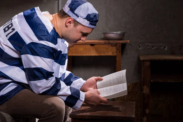 Joven preso con uniforme de prisión leyendo un libro o una b — Foto de Stock