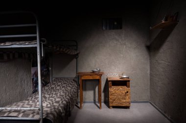 Dark empty jail cell with iron bunk bed and bedside table  clipart
