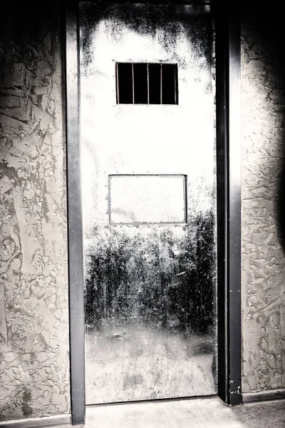 Железная дверь в тюремную камеру с отверстием для еды и окон — стоковое фото