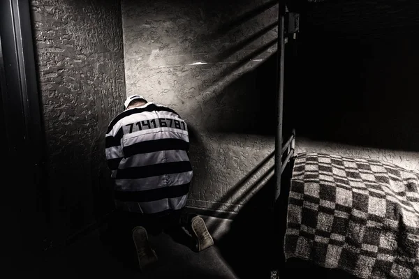 Prisoner is sitting in the corner in a small prison cell — Stock Photo, Image