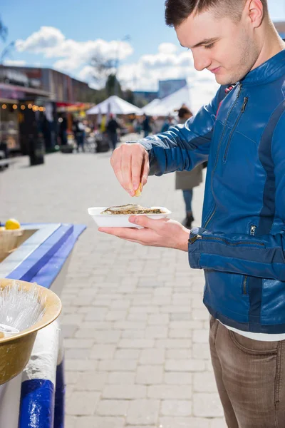 Ung man hålla en enda färska öppnade ostron och kramar ut — Stockfoto