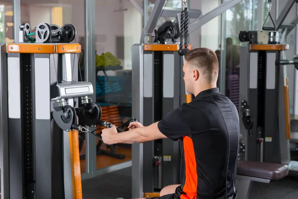 Handsome young fit man training on row machine — Stock Photo, Image