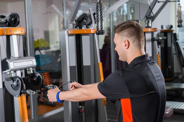 Young fit man training on row machine — Stock Photo, Image