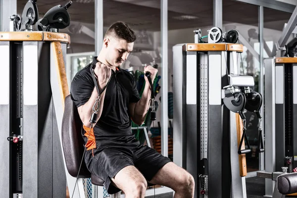 Ajuste o treinamento do homem na máquina moderna e exercitando-se na sala de ginástica — Fotografia de Stock
