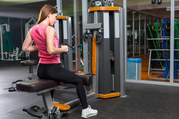 Sporty young woman training on row machine in gym — Stock Photo, Image