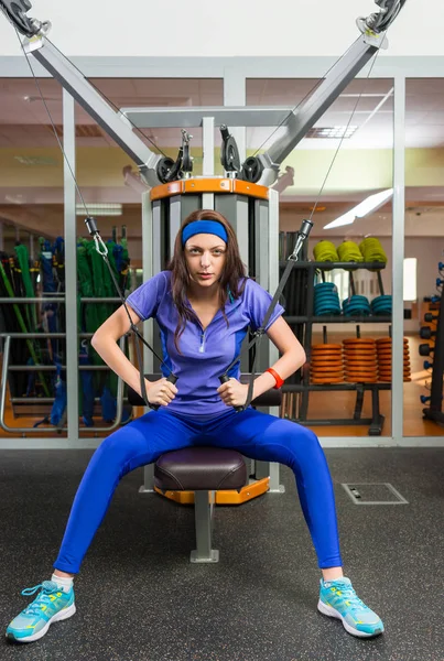 Treinamento de mulher jovem atraente na máquina de fileira no ginásio — Fotografia de Stock