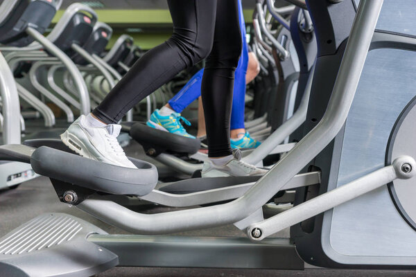 Close up view on legs of people exercising on the crosstrainer m