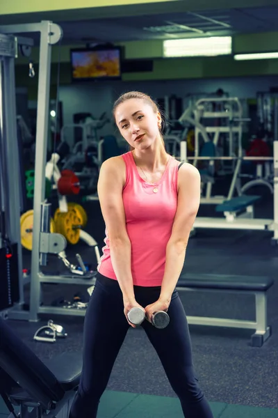 Sorrindo esportivo feminino em sportswear levantando alguns pesos — Fotografia de Stock