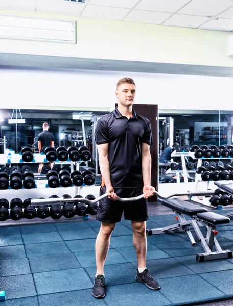 Guapo joven deportivo masculino en ropa deportiva levantamiento de la barra — Foto de Stock