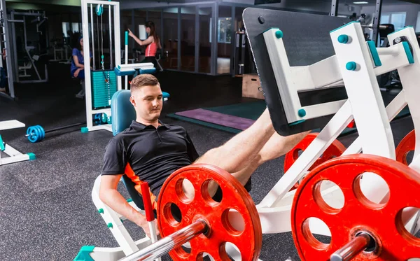Sportive man in sportswear working out on a machine — Stock Photo, Image