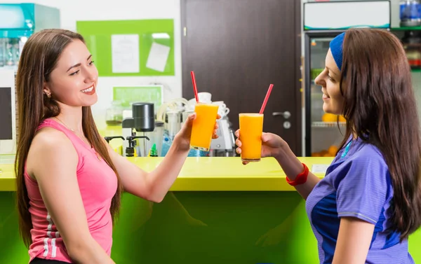 Two young happy women relaxing over drinks at the gym enjoying a — Stock Photo, Image