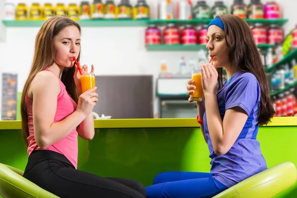 Young happy women relaxing over drinks at the gym enjoying a hea — Stock Photo, Image