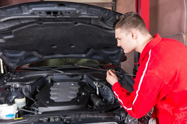 Mecânico de motor verificando o nível de óleo em um carro — Fotografia de Stock