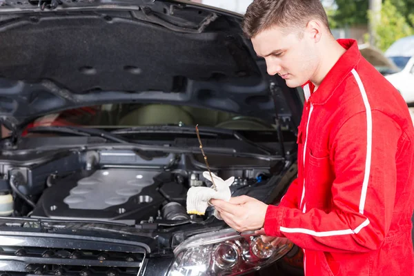 Young handsome motor mechanic wipes with a glove the dipstick af — Stock Photo, Image