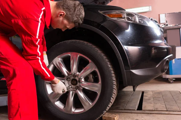 Närbild på manliga auto mekaniker står nära en svart sedan och s — Stockfoto