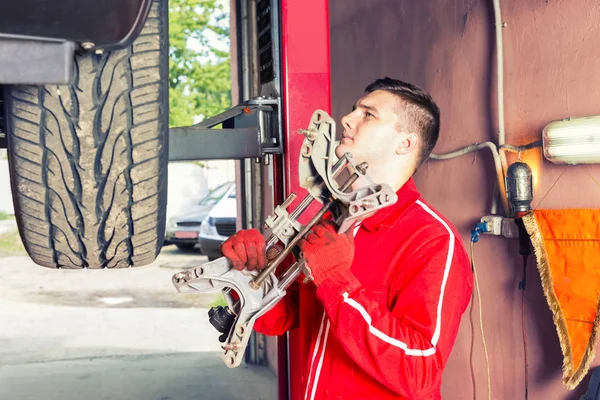 Young auto mechanic holding a piece of equipment in an automotiv — Stock Photo, Image